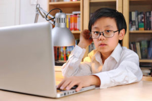 boy with glasses working on laptop