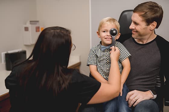 young boy getting eye exam with mom
