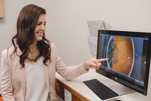woman pointing at 3d image of eye on computer screen