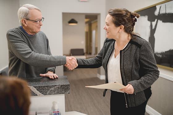 Woman eye doctor shaking hands with male senior patient